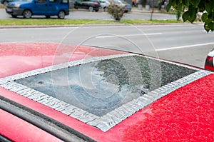 Damaged glass roof window or sunroof on the red car glued with duct tape to prevent water to come in the interior of the vehicle