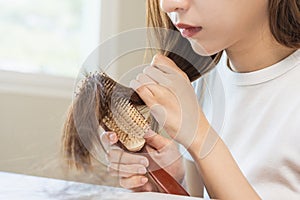 Damaged Hair, frustrated asian young woman, girl hand in holding brush splitting ends messy while combing hair, unbrushed dry long