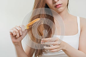 Damaged Hair, frustrated asian young woman, girl hand in holding brush splitting ends messy while combing hair, unbrushed dry long