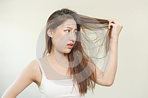 Damaged Hair, frustrated asian young woman, girl hand in holding splitting ends, messy unbrushed dry hair with face shock, long