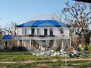 Damaged house with blue tarps on the roof and debris after Hurricane Katrina