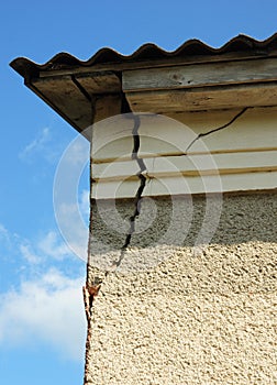 Damaged house stucco wall corner. Cracked Wall near Roof Construction.