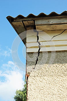 Damaged house stucco wall corner. Cracked Wall near Roof Construction. detail of damaged house corner dilapidated old building