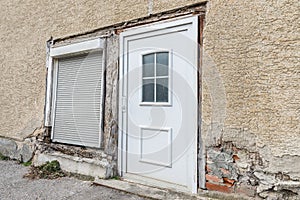 A damaged house wall and flaked exterior plaster with a large hole, Germany