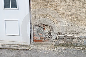 A damaged house wall and flaked exterior plaster with a large hole, Germany