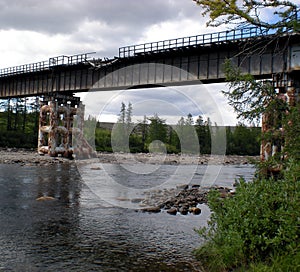 Damaged iron bridge over river. The old bridge