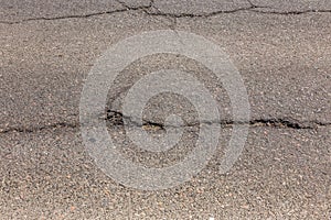 Damaged road, asphalt cracks. Asphalt with potholes and asphalt overflow spots. Very bad asphalt road with big holes. Scary