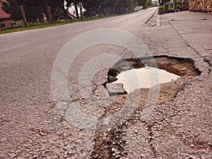 Damaged road surface with deep pothole.