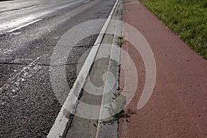 Damaged road, tire traces, sidewalk.