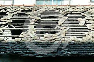 Damaged roof on old house with vintage tiles and hole.