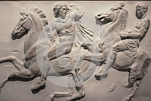 A damaged section of the Elgin Marbles relief originally on the Parthenon in Greece showing two men on horses in a battle