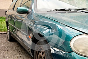 Damaged side door on a dark greencar after a traffic accident