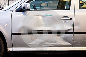 Damaged side door on a silver car after a small traffic accident