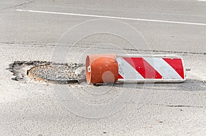Damaged street reconstruction or construction barricade caution red and white sign cover the open hole of manhole on the road as a