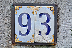 A damaged tile house number sign, showing the number ninety three