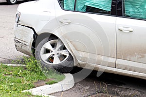 Damaged tire and bumper on white car. Result of car crash into the curb. Soft focus