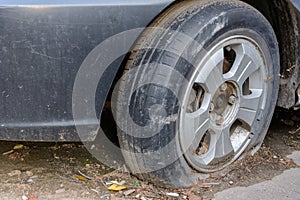 Damaged tire. The wheel of car tire leak. Flat tire waiting for repair. Abandoned car in the parking lot