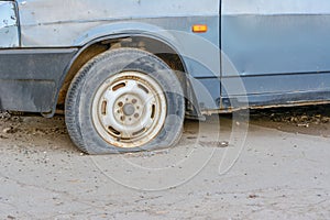 Damaged tire. The wheel of car tire leak. Flat tire waiting for repair. Abandoned car in the parking lot