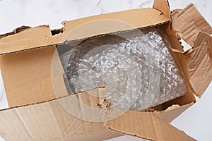 Damaged and torn open cardboard box for transporting things. Top view. Close-up. Bubble wrap keeps things and utensils