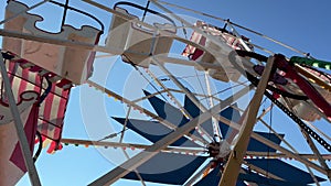 Damaged vintage circus ferris wheel with blue sky in the background