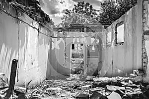 Damaged wall of domestic civilian house or building with hole and collapsed roof destroyed by grenade in the war zone after bombin