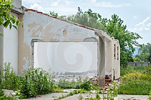 Damaged wall of domestic civilian house or building with hole and collapsed roof destroyed by grenade in the war zone after bombin