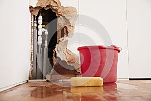 Damaged wall, exposed burst water pipes, sponge and bucket