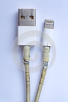 Damaged white usb cable plug and micro usb plug or Old Smart Phone Charger Cable broken on white acrylic background, Close up