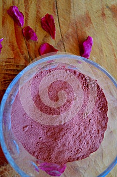 Damask rose powder closeup in glass bowl with petals