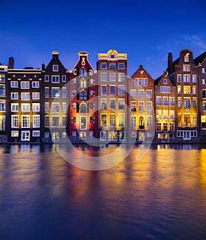 Damrak, Amsterdam, Netherlands. View of houses during sunset. The famous Dutch canals. A cityscape in the evening.