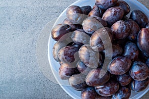 Damson Plums in Plastic Bowl.