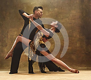 Dance ballroom couple in gold dress dancing on studio background.