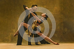 Dance ballroom couple in gold dress dancing on studio background.