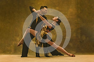 Dance ballroom couple in gold dress dancing on studio background. photo