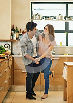 Dance and be happy. Shot of an affectionate young couple dancing in the kitchen.