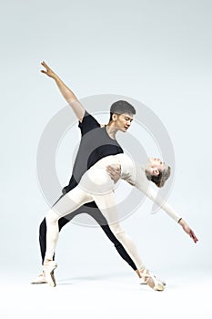 Dance Couple of Asian Young Man and Caucasian Woman Performing As Ballet Dancers Over Grey in Studio During Suppots As Classical