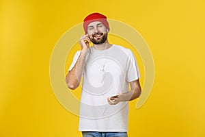 Dance. Handsome young stylish man in headphones holding mobile phone and dancing while standing against yellow