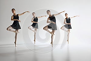 Dance in harmony. Beautiful teen girls, ballerinas in black leotards and pointe in motion, dancing against gray studio photo