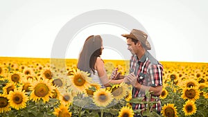 Dance man in a hat and a girl on the field with yellow sunflowers