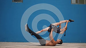 Dance partners demonstrating sensual dance pattern with acrobatics in slow motion on blue background. Dancing outdoors