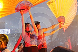 Dance performer raising arms with paper fans