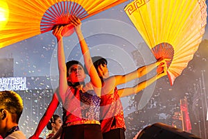 Dance performer raising arms with paper fans