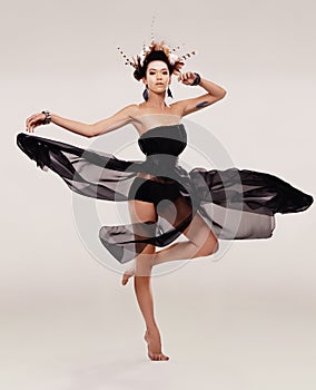Dance - where the body and soul meet. A young woman in a chiffon dress dancing while isolated on a plain background.