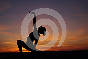 dancer in the dance does the splits in the air against the sunset.