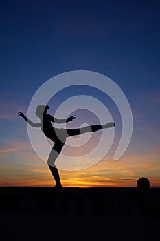 dancer in the dance does the splits in the air against the sunset.