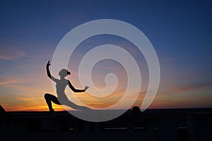 dancer in the dance does the splits in the air against the sunset