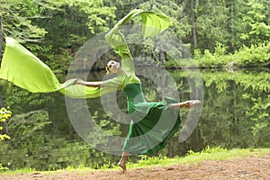 Dancer in green dress with very long sleeves in Connecticut woods
