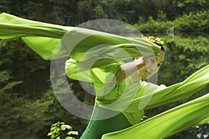 Dancer in green dress with very long sleeves in Connecticut woods