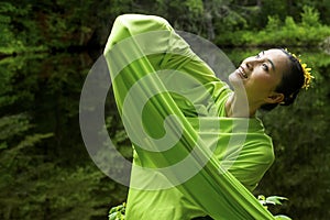 Dancer in green dress with very long sleeves in Connecticut woods