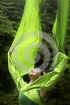 Dancer in green dress with very long sleeves in Connecticut woods